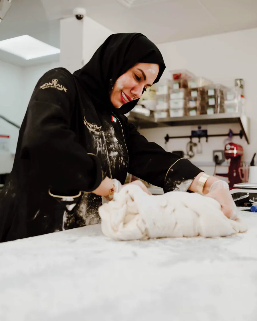 Chef Mariam Al Mansoori kneading dough on a flour-dusted marble counter